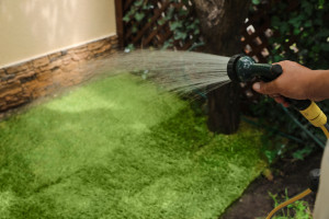 Man watering unrolled grass sods at backyard, closeup