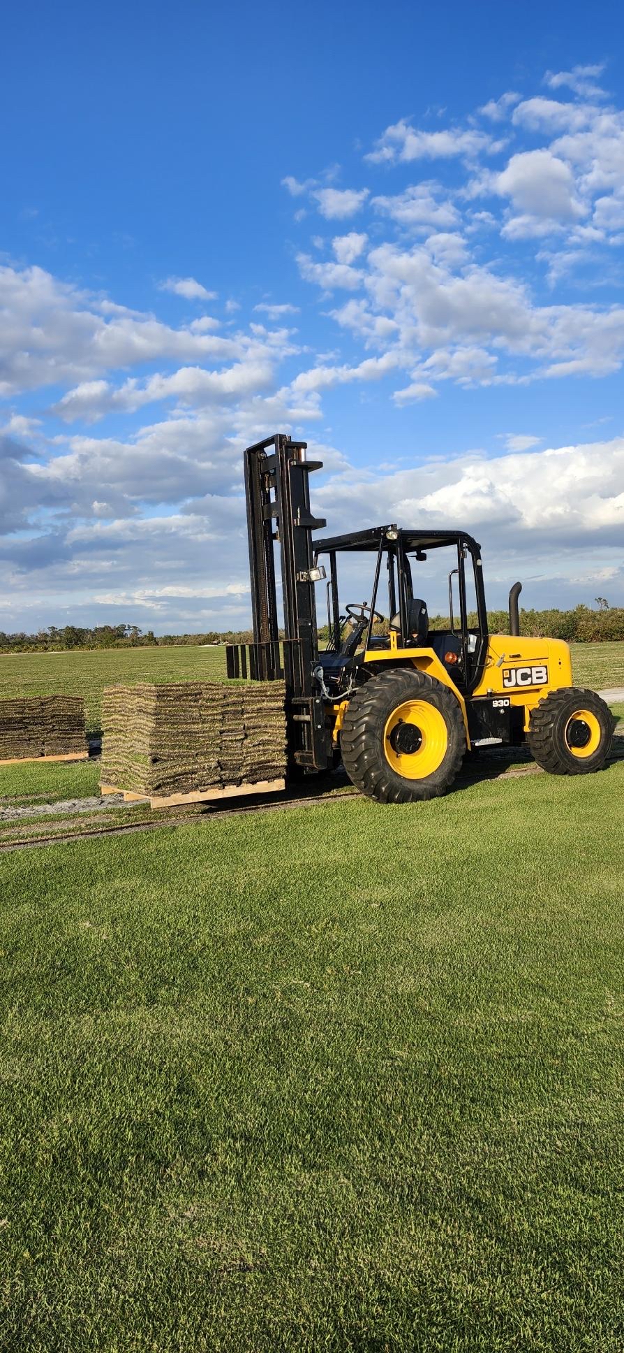 Forklift loading pallets of CitraZoy Zoysia sod beside a field at the Bayside Sod farm